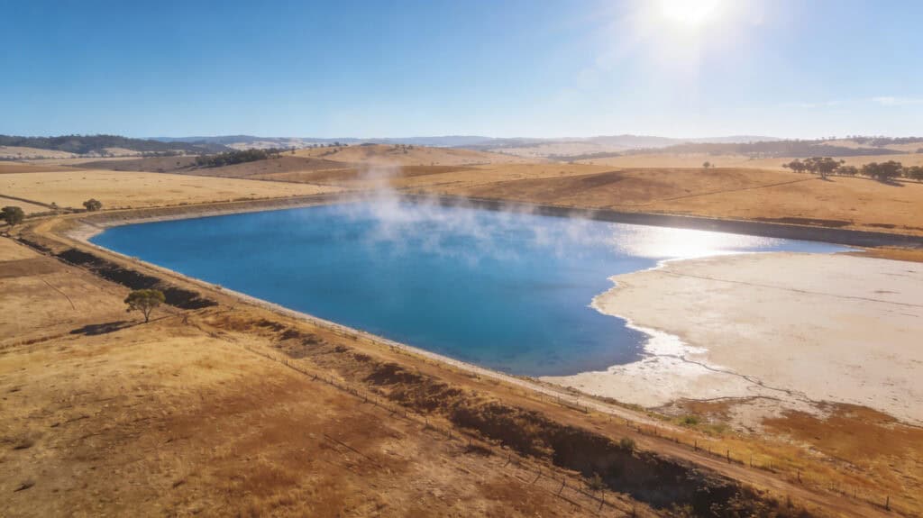 Large reservoir demonstrating evaporation with visible water vapor in a rural landscape.